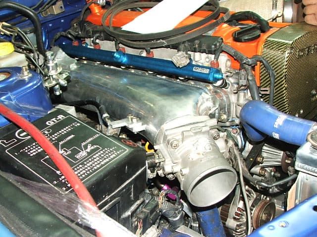 A NOZZS RB series intake manifold fitted to an RB26. The water outlet pipe clears the manifold. For those running larger batteries, you may require a battery relocation or a smaller battery.