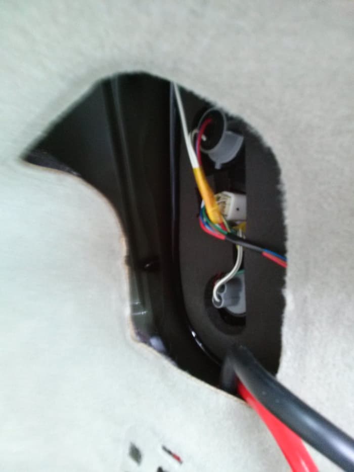 Route both the positive and negative power cables through the right rear taillight access hole.