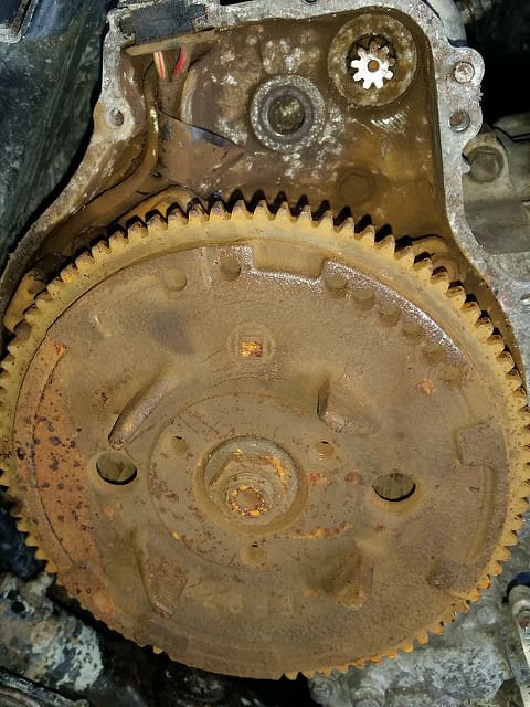The starter motor pinion gear meshes with the flywheel on the back of the engine.