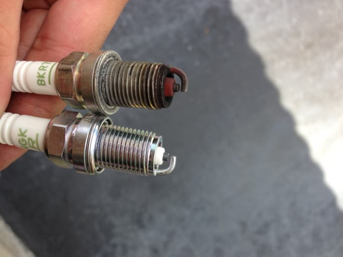 Used plug from a previous swap next to new plug. Red-tint caused by Gold Eagle 104 Octane Booster. No problem.