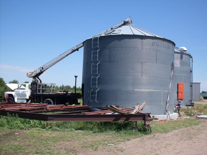 A nearly completed bin. This one lacks a ring of sheets, and is being held down by the boomtruck, as it's not anchored to the cement. Ever watched a kite take off in the wind? A grain bin will do the same thing.