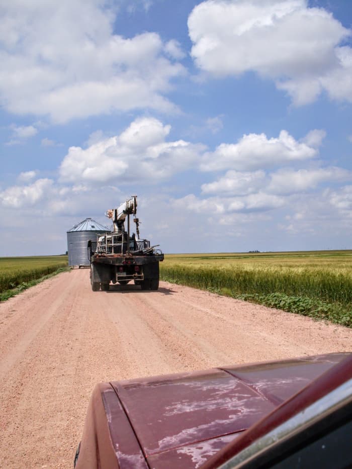 A convoy: First went our friend Les, with the shortened bin on a big trailer. Next came my husband, in the boomtruck, which we used to load and unload the bin. Last, came the kids and I, in the car.