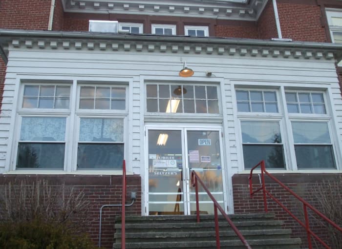 Lace curtains adorn this red brick former schoolhouse, now the Jubilee thrift shop.