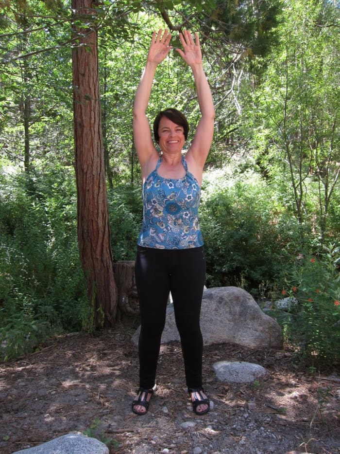 Bring your arms straight up and over your head. Reach to the sky. Continue to hold your breath.