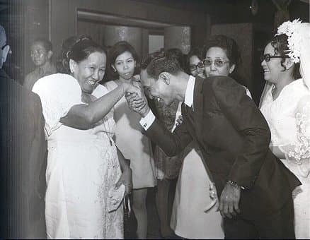 A son taking the hand of his mom and putting it to his forehead to show respect. This is an example of the Filipino tradition of mano po.