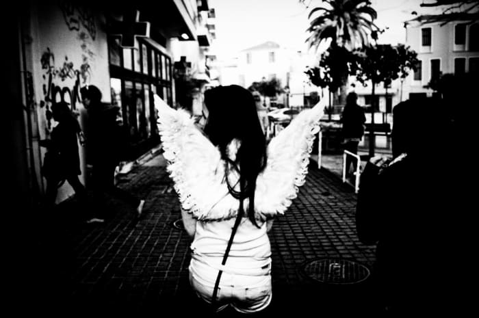 This everyday angel combs the boulevard during a festival, looking lost.