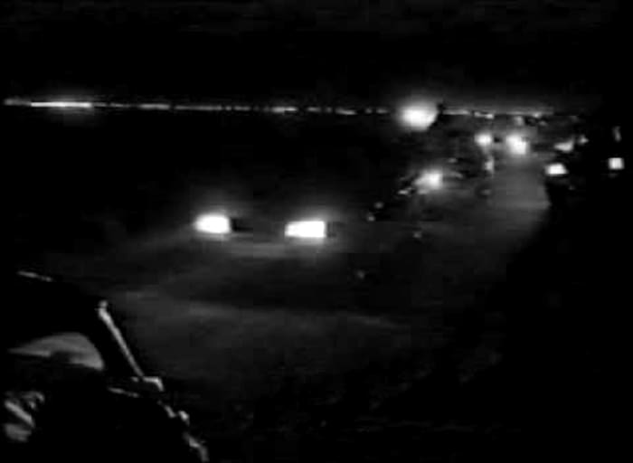 The familiar sight of car headlights on the motorway as a convoy of ravers make their way to a party (1989).