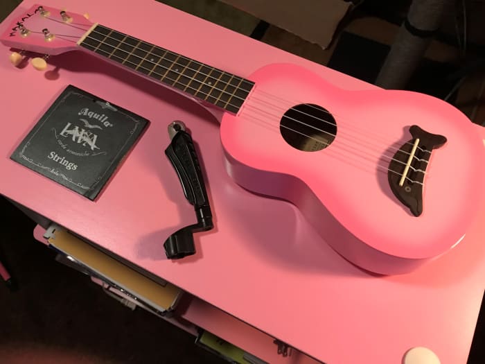 You need you ukulele, new strings, a string winder (optional), a wirecutter (string winder with built-in string cutter shown), and a tuner (option, not pictured here)