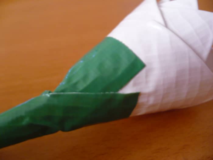 Hold the tape-wrapped pipe cleaner against the base of the flower so that it sticks out like a stem.