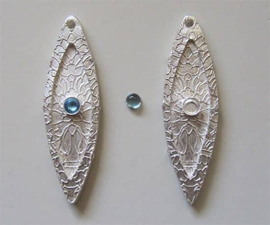 Silver marquise earring drops embedded with commercial fine silver bezel cups before firing, to be set with calibrated natural blue topaz cabochons after firing.