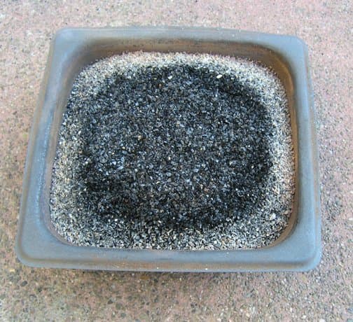 Stainless steel firing pan with ash topped activated carbon after firing