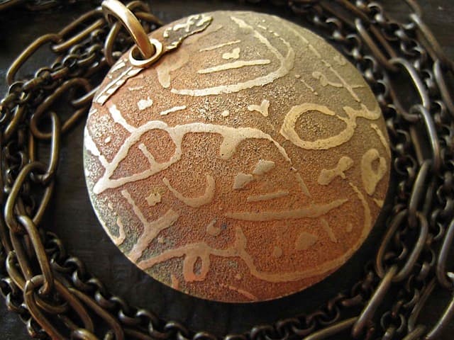 Bronze lentil pendant with tear-away textures