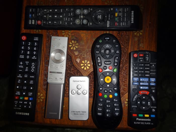 The top remote is for the sound system. The remotes below, from left to right, are TV, universal remote, optical audio switch, cable TV, and Blu-ray player.