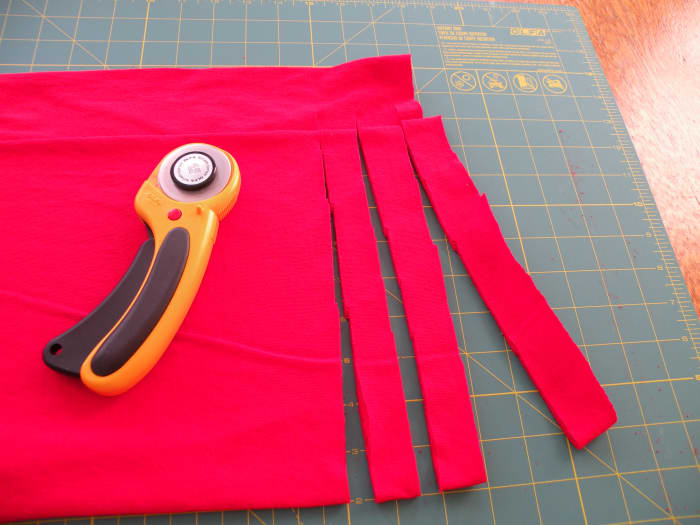 Begin to cut 3/4 inch slits in the fabric, but stop short of cutting the strips completely off the shirt.