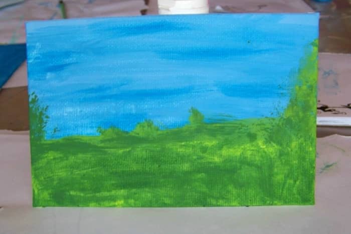 This acrylic painting by 7-year-old, Alesia, shows her two-tone sky, a two-tone grassy field. Now we are going to see how she made trees.
