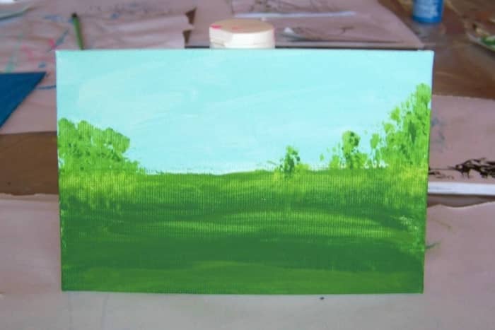 This landscape by 5 yr old, Aaliyah, features a light blue sky with white highlights and a darker green grass field.