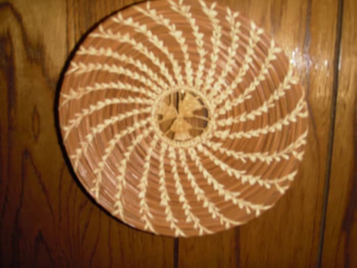 This decorative plate by J. Simpson has a slice of black walnut shell sewn into the starting coil.