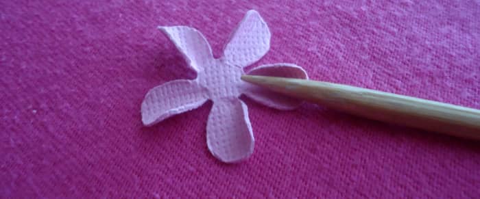 Now take another punched flower and use the skewer to curl the petal inward on one side. Repeat with each petal.