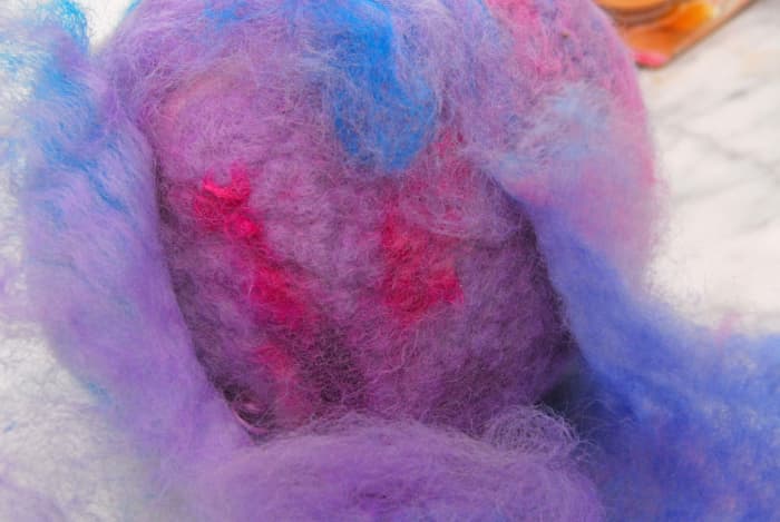 Wrapping the ball in a layer of Merino Wool which was stripped from some of the partially fulled fibers which appear above.