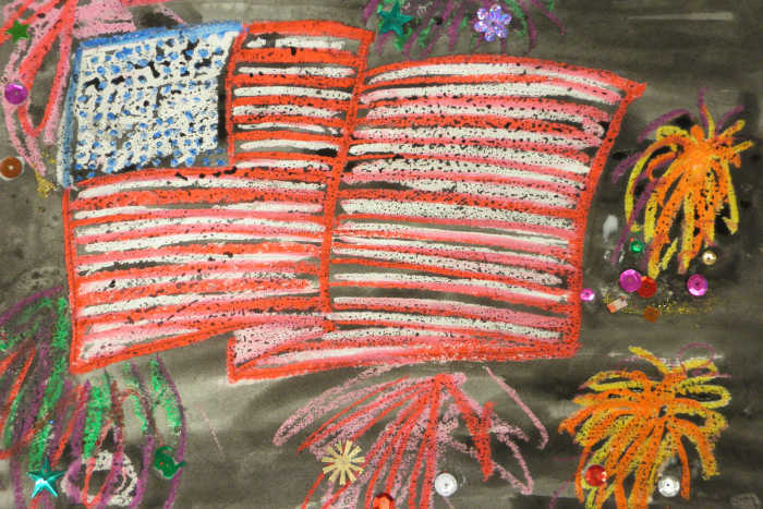 Painting of an American flag. In this one, the American flag and fireworks were done with oil pastels, then a watercolor wash was added for the background night sky. The optional sparkles were also added.