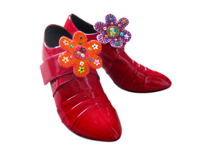 Add a large pelican clasp on the back of each flower, sewn on in similar manner to a brooch, so they can be added to shoes.