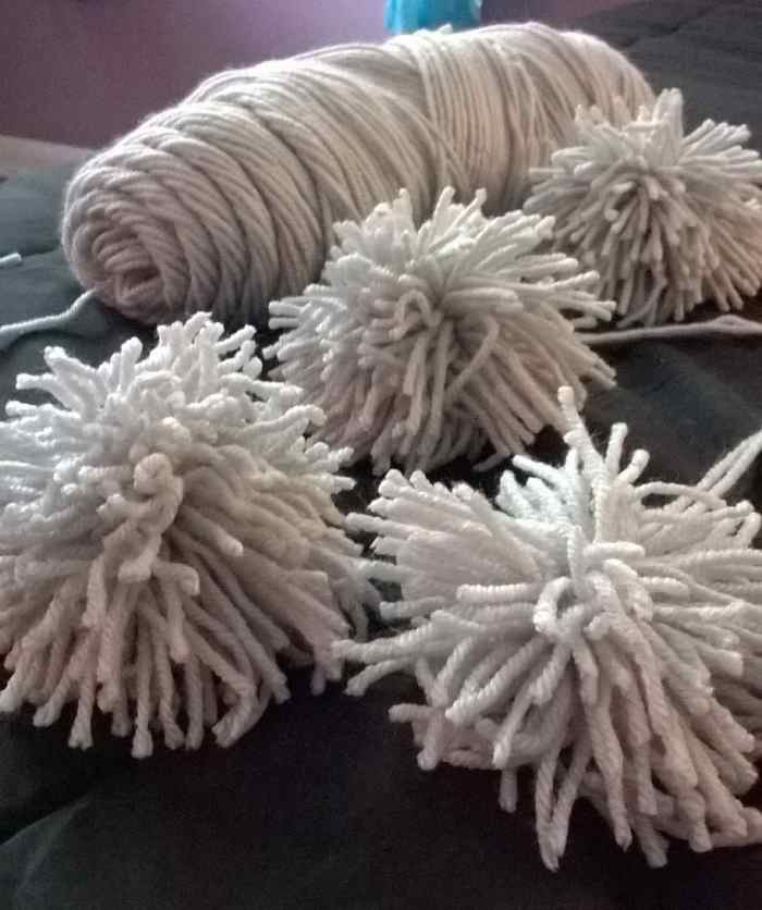 Four finished pom poms. Before we can use the pom poms to make a rug, we need to make them!