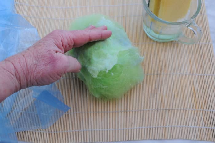 Dampen down the fibers gently with hot soapy water and then press them flat against the ball.
