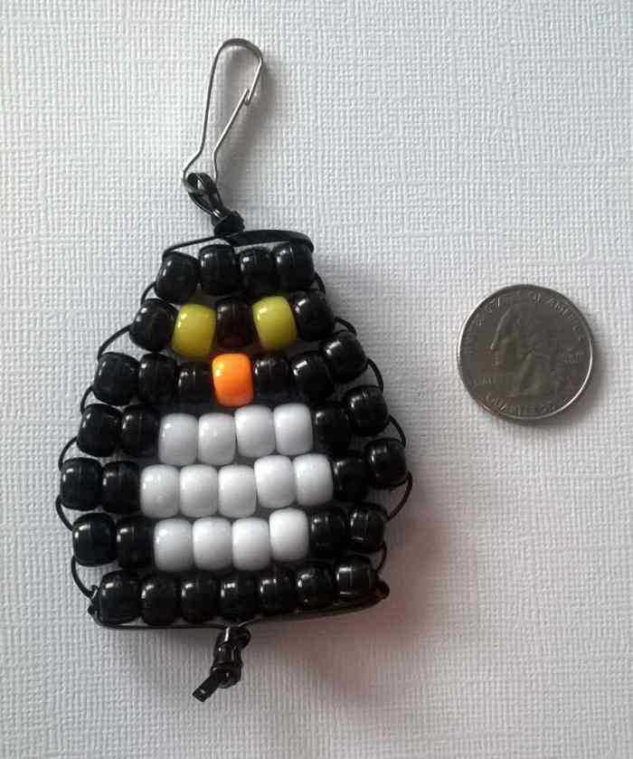 You could make any animal shape—like a penguin, for example! This beaded penguin key chain is placed next to a U.S. quarter to show size.