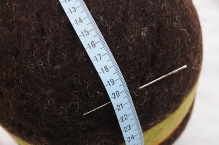 Marking the cutting line with a tape measure, felting needle indicates the start line
