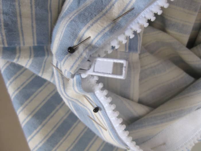 Pinning around the bottom end of the zip. Unzip until it reaches the end of the pillowcase (even if there is still some zip hanging off on the inside), then pin into place.