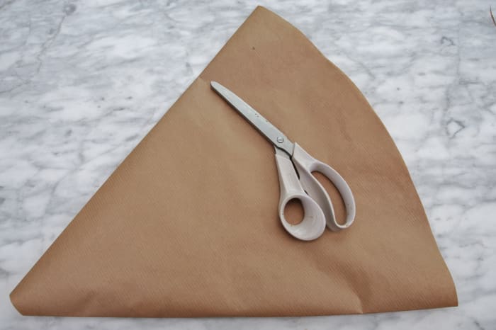 The flattened cone of paper will become the pattern for this project. Fold in one inch from one side