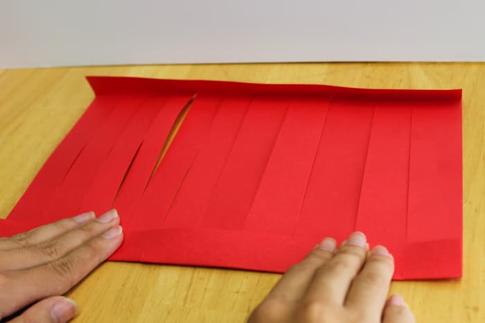 Fold the top and bottom of the lantern towards you. When you fasten them to the tube in the middle, the center strips will bulge out in a round shape.
