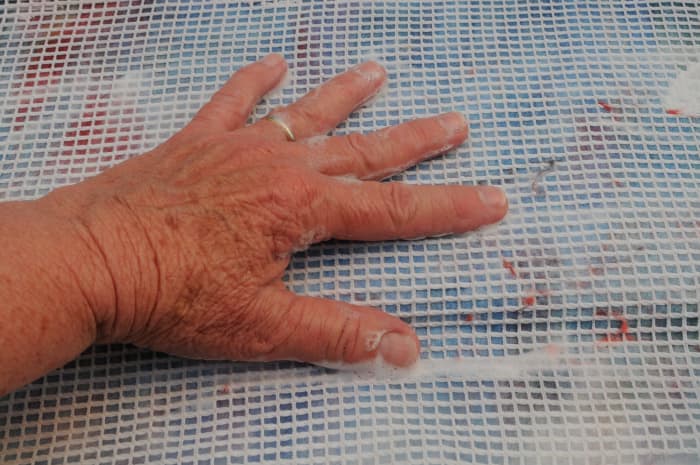 Cover with netting. Wet with warm soapy water. Smooth out the fibers and then turn the template over. Repeat on the other side with another layer of fine fibers.
