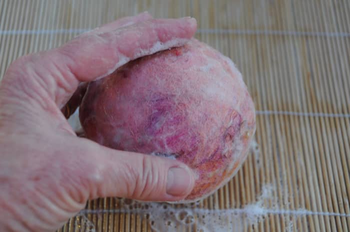 Smooth out the fibers on the surface of the ball by rolling them on the bamboo blind.