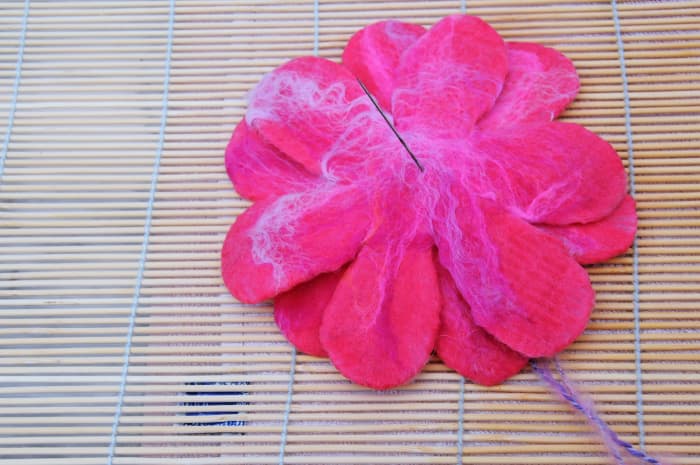 Stitch right through all 3 layers of the flower petals with a needle previously threaded with knitting wool