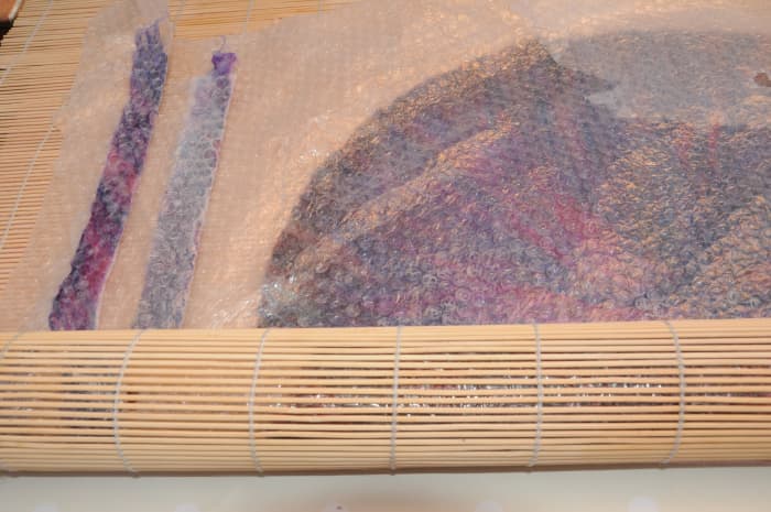 Add the 2 jacket or cape ties to the contents of the bamboo blind so that they can be rolled together.