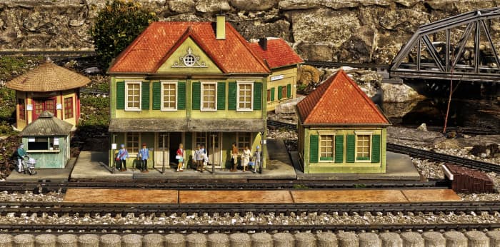 Model buildings are very popular for use in model train railways platforms. The train, all types of buildings, vehicles, and people are also built to scale whenever possible. This picture is an illustration of a train depot with its miniature people.