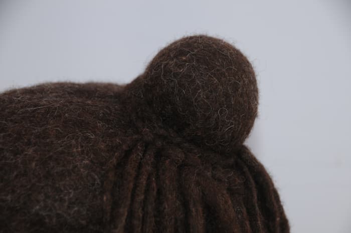Make a plait using 3 dreadlocks. Attach it loosely to the bun after removing the elastic band and then attach the other half of the dreadlocks to the plait. Tie tightly around the bun.