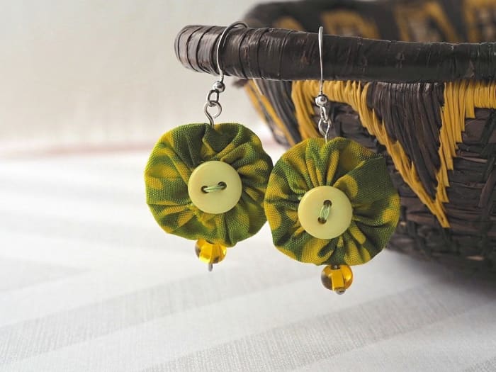 Using this easy tutorial, make your own pair of these unique yo yo earrings with a few fabric scraps, buttons, beads and jewelry making supplies.