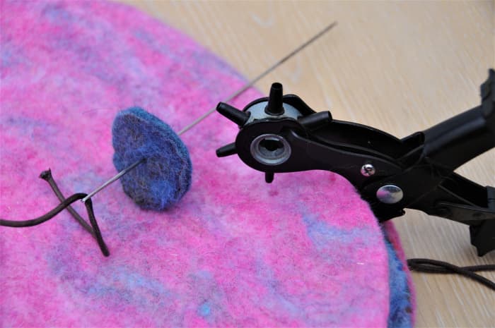 Cut 1 tiny hole in the center of the 2 felt pieces using a leather punch or tiny scissors. Placement can be sourced using a large eyed doll needle.