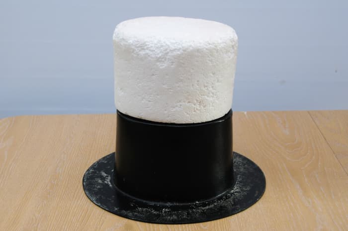 The polystyrene hat block balanced on the hat shaper. This was used inside the waste-paper bin sleeve to increase the height of the hat.