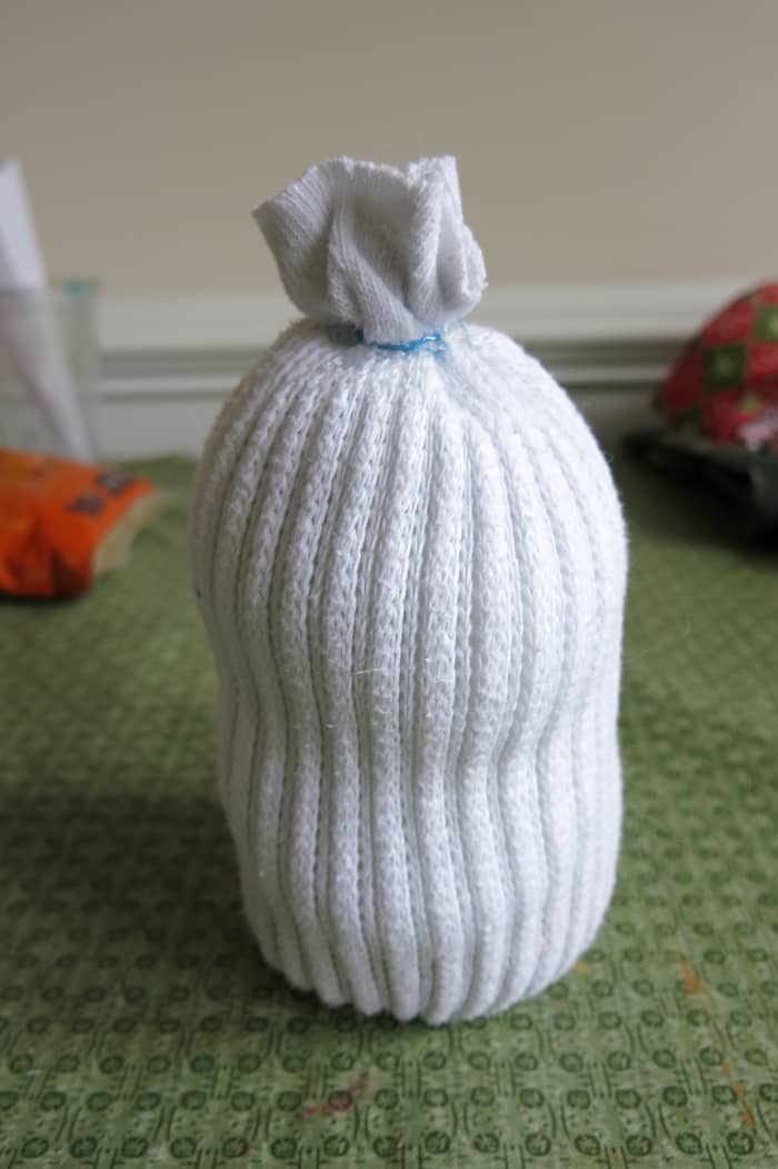 Fill the body of your sock snowman with fiber fill or cotton balls before closing it off with a rubber band or thread.