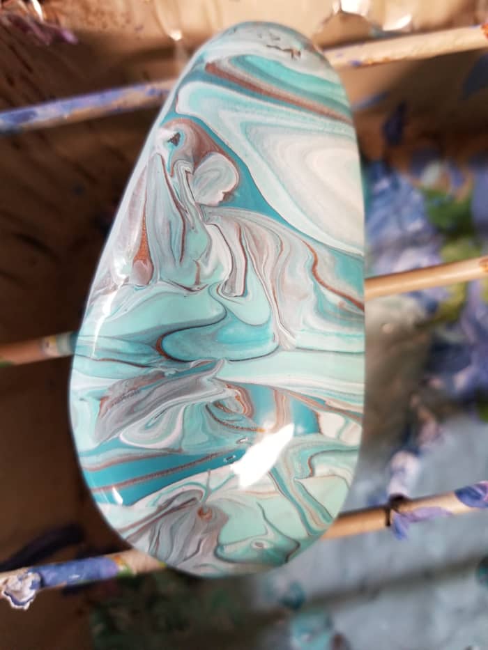 To spread the paint, gently tilt the rock in different directions but don't go overboard.