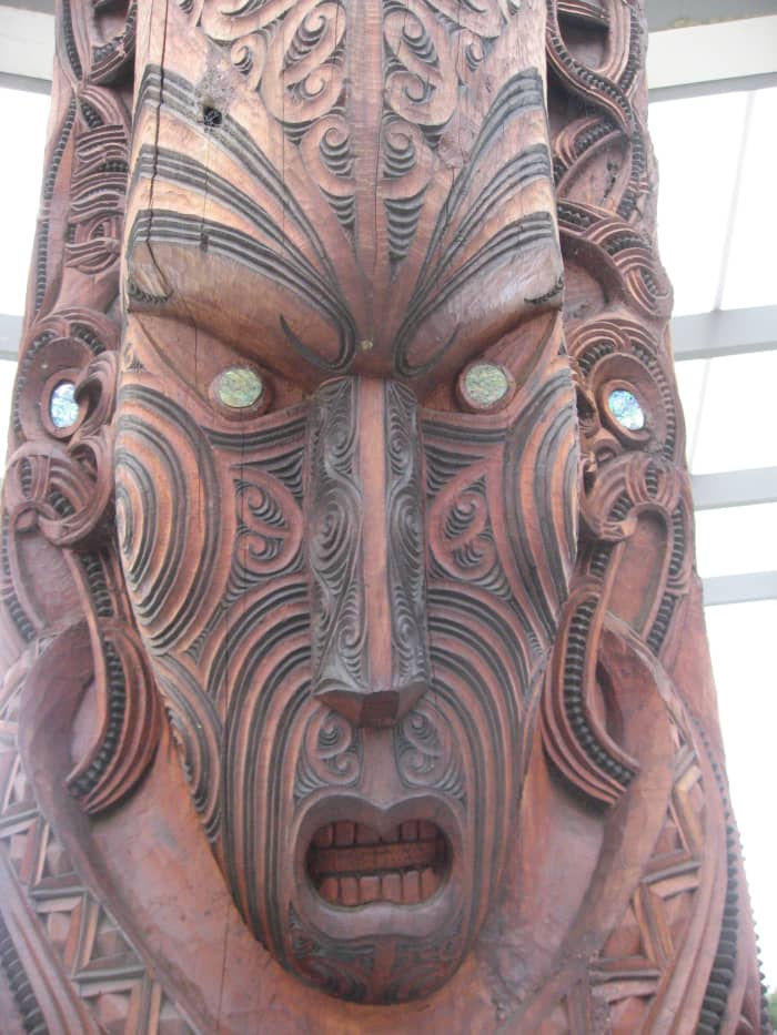 Face detail from Maori totem pole at Rotorua Maori Cultural Ceter. Note the simple facial features with elaborate facial lines to mimic the Maroir identifying tattoos.