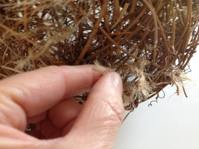 Weave the fabric and the twine through the grapevines doing the same with your other materials until the ball is completely covered.