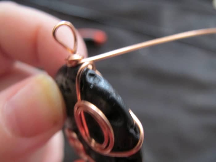 Once again, criss cross the wire around the back of the stone; this time, wrap it tightly around the coil on the necklace bail.