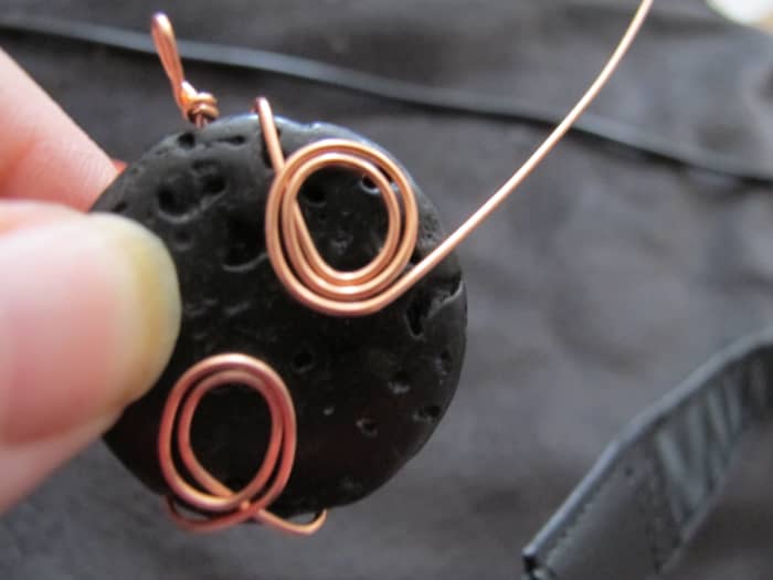 Criss cross the wire around the back of the stone so that it comes over to the opposite side on the upper portion of the stone; form another spiral.