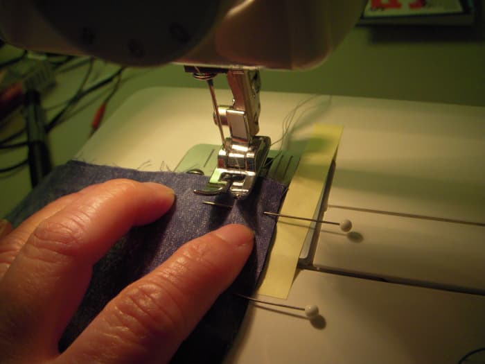 Place the garment that you're sewing under the sewing foot, lining up the sewing edge to your 5/8" mark. The sewing needle is close to the top edge, or the start of your seam.