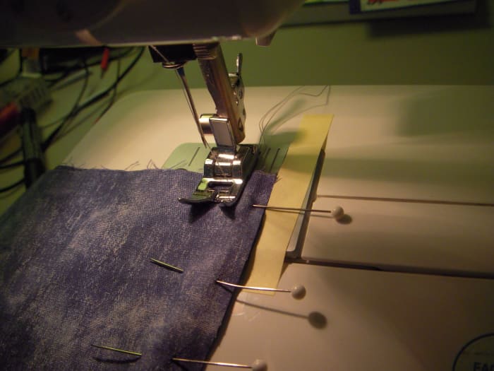 Lower the sewing foot. Ensure that your seam edge lines up against the 5/8" mark, the thread tails hang away from you.