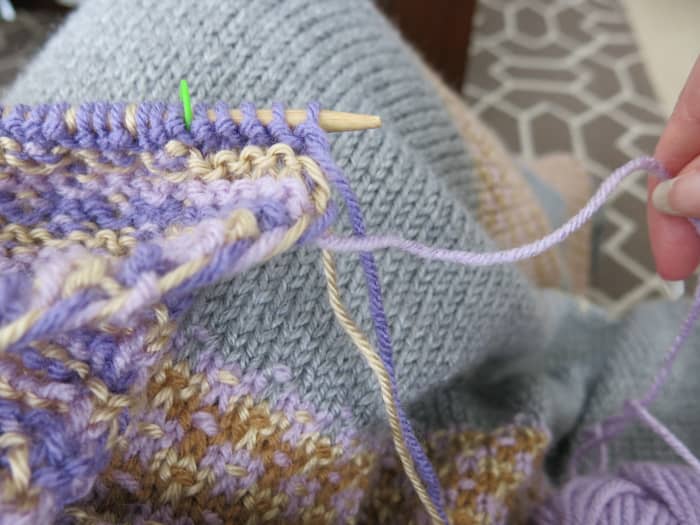 Bring your working yarn out and around the other colors to create a twist of the yarn up the edge of your blanket.